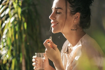 Frau nimmt eine Kapsel mit einem Glas Wasser ein