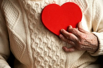 Ältere Person hält ein rotes Herzsymbol in der Hand