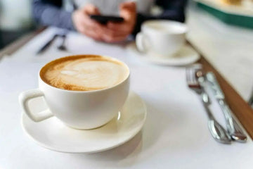 Tasse Kaffee und geröstete Kaffeebohnen auf einem Tisch