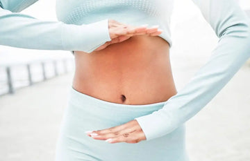 Frau hält ihre Hände wegen Verdauungsbeschwerden auf den Bauch