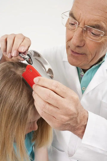 Ärztin untersucht Haare und Kopfhaut mit einer Lupe