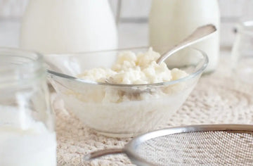 Kefirkörner neben einem Glas fermentiertem Kefir