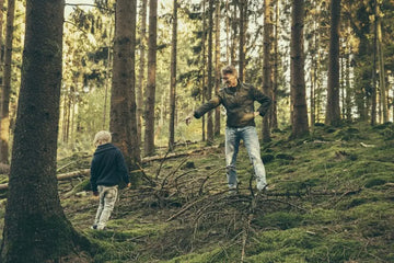 Erwachsener sammelt mit einem Kind Pilze im Wald