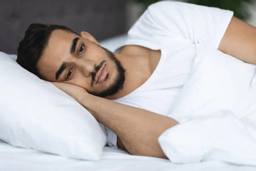 Wacher Mann liegt nachts unruhig im Bett