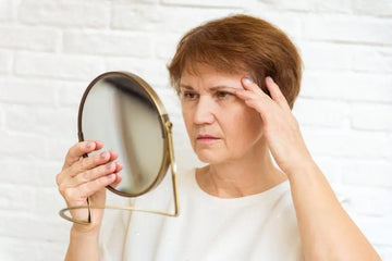Ältere Frau blickt in einen Spiegel als Symbol für Anti-Aging-Werbung