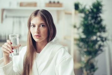 Frau trinkt Wasser in der Küche als Symbol für Detoxwerbung